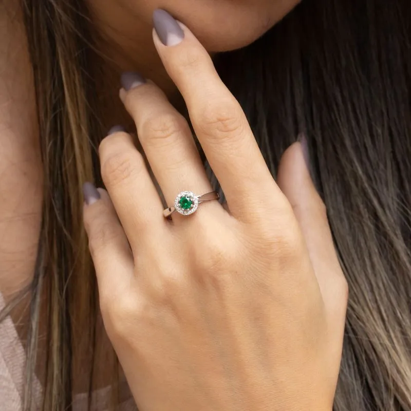 round yellow gold ring with white zircons and a green zircon in the center