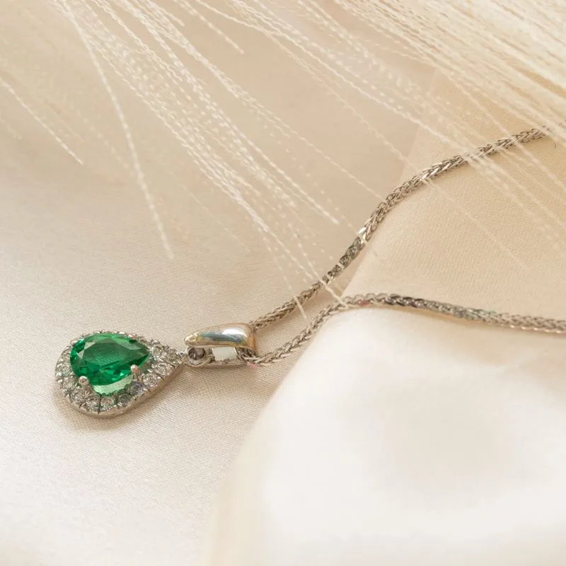 White gold drop necklace with white zircons and a green zircon in the center